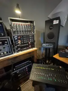 Racks of professional studio equipment including Neve and Millenia preamps, PMC speakers, and an Avid S3 control surface used during sessions